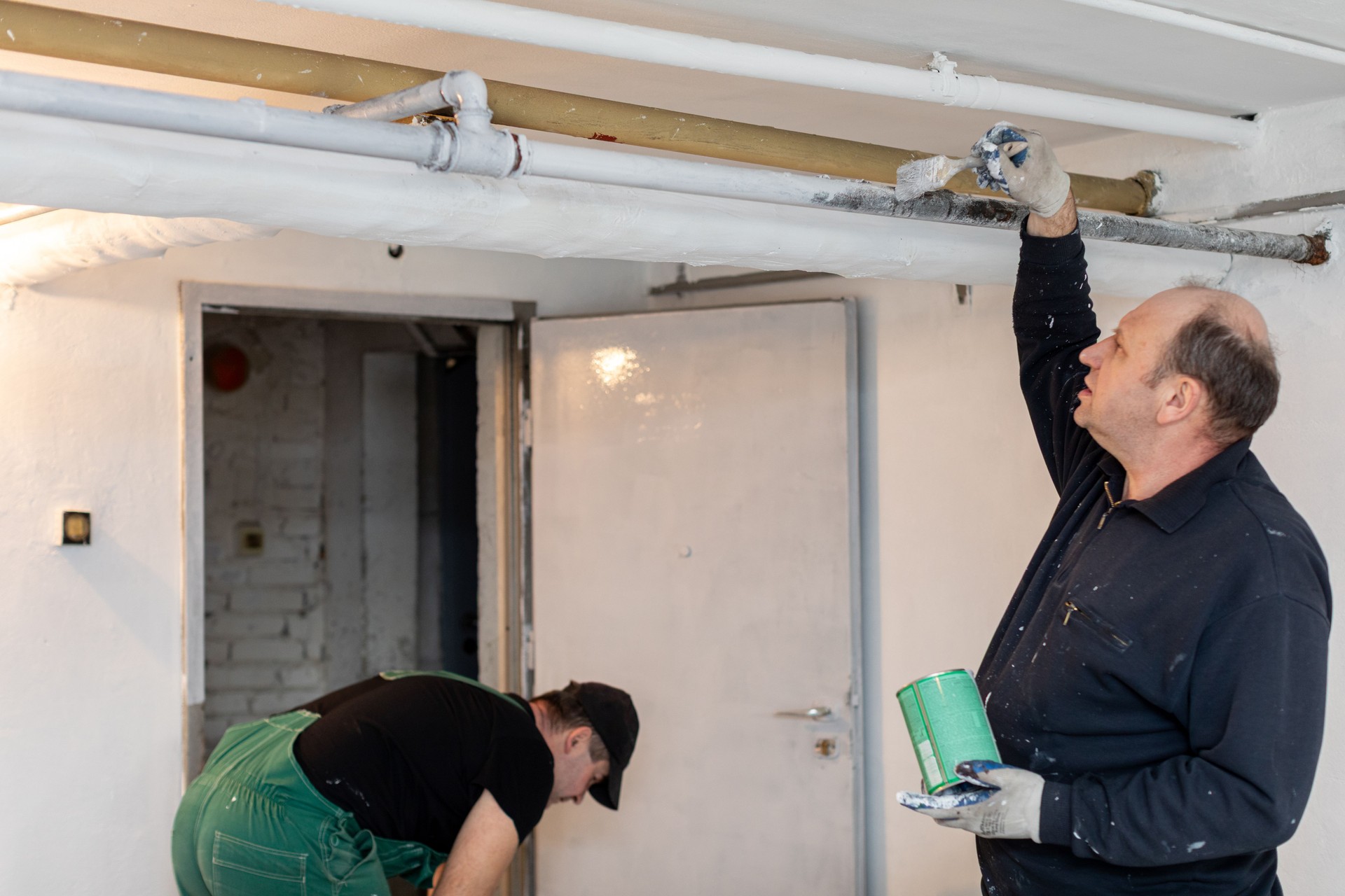 Two professionals are painting and renovating an interior space collaboratively, showcasing skills